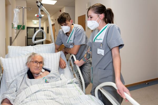 Foto Patientin im Krankenbett neben Pflegepersonal